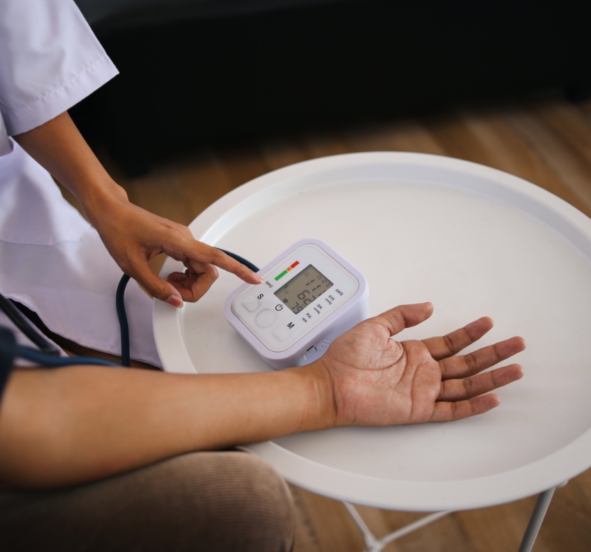 A healthcare professional taking a blood pressure reading; only hands and equipment are shown